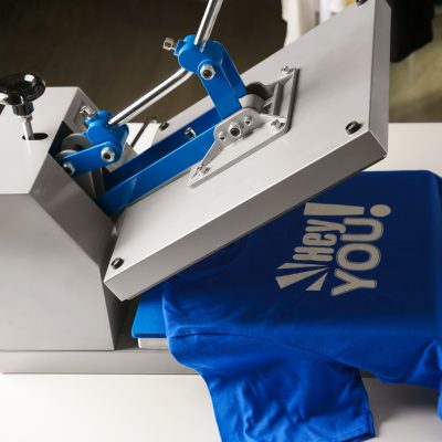 Printing logo. Heat press with blue t-shirt on white table